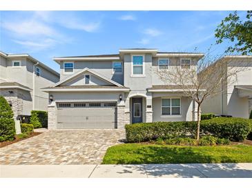 Charming two-story home featuring a brick driveway, a two-car garage, and manicured landscaping at 321 Auburn Ave, Kissimmee, FL 34747