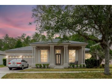 Inviting single-story home featuring stately columns, lush landscaping, and an attached two-car garage at 10292 Kristen Park Dr, Orlando, FL 32832