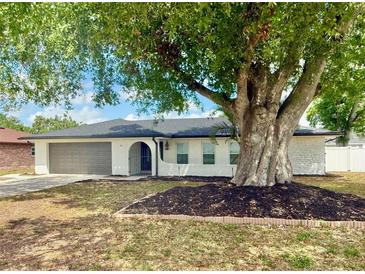 Charming home featuring a huge shade tree, manicured landscaping, and a two-car garage at 66 Alachua Dr, Winter Haven, FL 33884