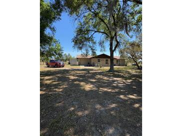 Sprawling property featuring home with mature trees and large front yard, parked red pickup truck adds rustic touch at 8955 Rhoden Loop W Rd, Fort Meade, FL 33841