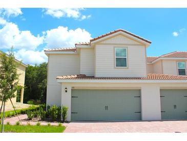 Charming two-story townhome with a red tile roof and a two-car garage at 591 Bay Leaf Dr, Poinciana, FL 34759