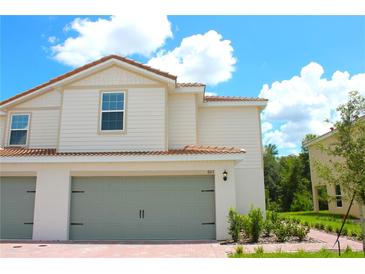 Charming two-story home with neutral siding, attached two-car garage, and beautiful landscaping at 603 Bay Leaf Dr, Poinciana, FL 34759