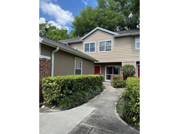 Charming two-story townhome with a walkway leading to the red front door and lush green bushes lining the path at 665 Oak Harbour Dr # 115, Altamonte Springs, FL 32701