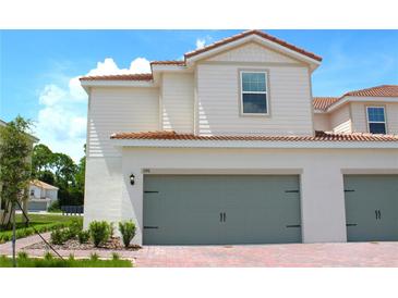 Exterior shot showcasing the two-story townhome with a two-car garage and brick-paved driveway at 596 Bay Leaf Dr, Poinciana, FL 34759