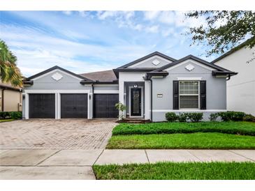 Charming single-story home featuring a three-car garage, manicured lawn, and attractive exterior color scheme at 7071 Spring Park Dr, Winter Garden, FL 34787
