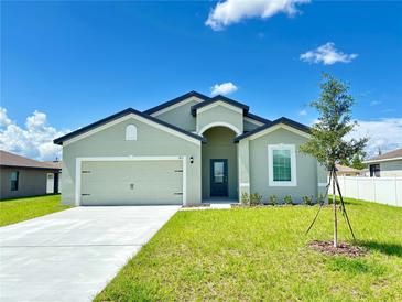 Charming single-story home featuring a two-car garage and a beautifully landscaped front yard on a sunny day at 385 Begonia Ct, Poinciana, FL 34759
