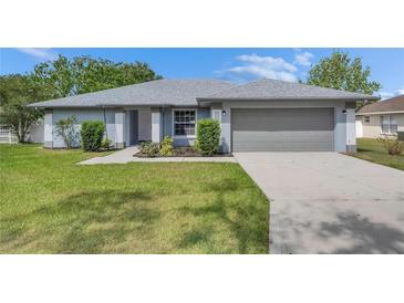Charming single-story home featuring a well-maintained lawn, gray exterior, and a two-car garage at 5349 Hidden Oaks Dr, Lakeland, FL 33811
