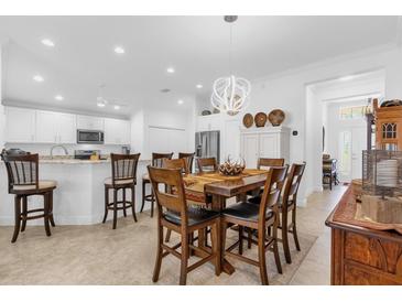 Bright dining area featuring an elegant chandelier, a wooden table with chairs, and access to the kitchen at 10367 Addison Shore Way, Oxford, FL 34484