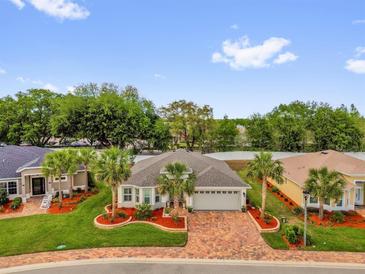 Beautiful single-story home featuring well-manicured landscaping and a paver driveway at 10367 Addison Shore Way, Oxford, FL 34484