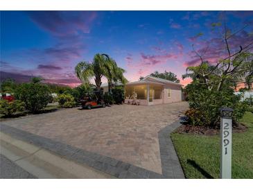 Charming home at sunset featuring a golf cart, brick driveway, manicured lawn and mature landscaping at 2991 Wood Duck Dr, Polk City, FL 33868
