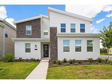 Contemporary two-story home featuring stone accents, a modern design, manicured landscaping, and a welcoming walkway at 4149 Paragraph Dr, Kissimmee, FL 34746