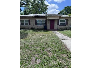 Modest single-story home with a pathway leading to a vibrant pink front door and windows with dark shutters at 1211 Ne 4Th St, Mulberry, FL 33860