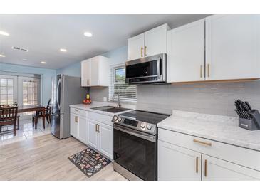 Modern kitchen with white cabinets, stainless steel appliances, tile backsplash, and an adjacent dining area at 820 Lamp Post Ln, Lakeland, FL 33809