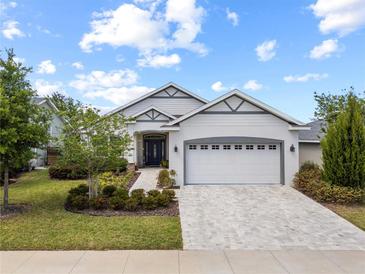 Charming single-story home featuring a manicured lawn and a two-car garage at 5008 Ne 125Th Loop, Oxford, FL 34484