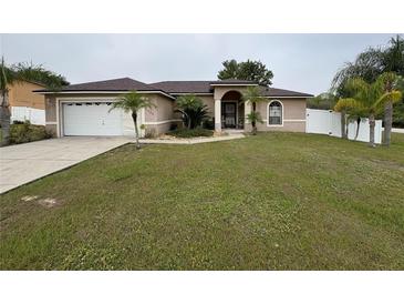 Charming single-story home featuring a two-car garage, palm trees, and well-maintained landscaping at 1500 Fort Meade Pl, Poinciana, FL 34759