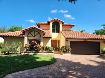 Charming home featuring a red tile roof, brick driveway, manicured lawn and lush landscaping at 8212 Borgia Ct, Orlando, FL 32836