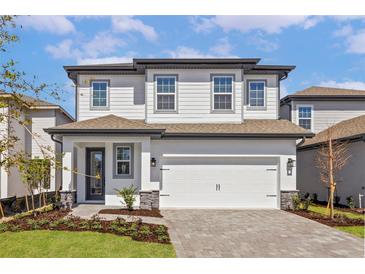 Two-story home with white siding, a two-car garage, and professionally landscaped front yard at 7744 Somersworth Dr, Kissimmee, FL 34747