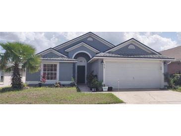 Charming single-story home featuring a well-manicured lawn and a two-car garage at 210 Cheshire Way, Davenport, FL 33897