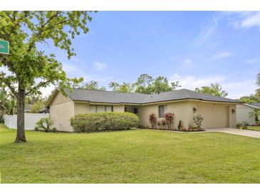 Charming single-story home with a well-maintained lawn, landscaping, and attached garage at 100 Essex Dr, Longwood, FL 32779