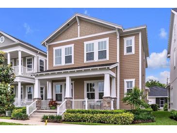 Charming two-story home with a welcoming front porch and manicured landscaping at 7418 Barrier Cove Way, Celebration, FL 34747
