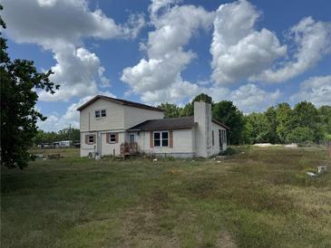 A two-story home has neutral siding, and a chimney sits on the stuccoed section at 10931 Pathfinder Trl, Lakeland, FL 33809