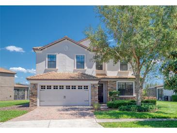 Charming two-story home with a stone-accented facade, tile roof, manicured lawn, and attached two-car garage at 1401 Wexford Way, Davenport, FL 33896