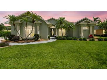 Landscaped front yard with palm trees and a circular driveway leading to a light green home at 5446 Highlands Vista Cir, Lakeland, FL 33812