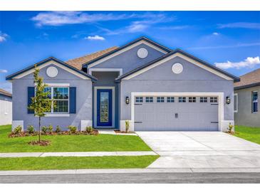 Charming single-Gathering home with a well-manicured lawn and two-car garage on a sunny day at 3319 Chinotto Dr, Lake Alfred, FL 33850
