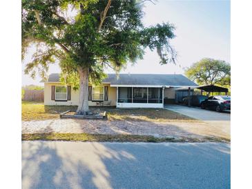 Charming single-story home with a large front tree and a screened-in porch, offering curb appeal at 4746 Wales St, Lake Wales, FL 33859