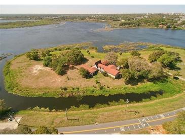 Expansive aerial view of a unique home on an island, surrounded by a serene lake and lush greenery at 201 Lake Bonny E Dr, Lakeland, FL 33801