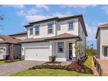 Charming two-story home with a two-car garage, gray trim, brick driveway and manicured front lawn at 7724 Somersworth Dr, Kissimmee, FL 34747