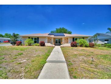 Charming single-story home featuring a tile roof, solar panels, manicured landscaping, and a paved walkway to the entrance at 53 Paine Dr, Winter Haven, FL 33884