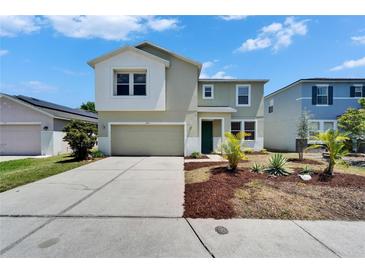 Two-story home boasts a well-manicured front yard with mature landscaping and an attached two-car garage at 2415 Brownwood Dr, Mulberry, FL 33860