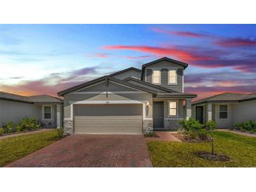 Charming two-story home with a brick driveway, gray exterior, and well-manicured lawn at 1859 Carnostie Rd, Winter Haven, FL 33884