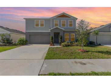 Charming two-story home with a well-manicured lawn, inviting entrance and neutral color scheme under a colorful sky at 1646 Seth Dr, Winter Haven, FL 33880