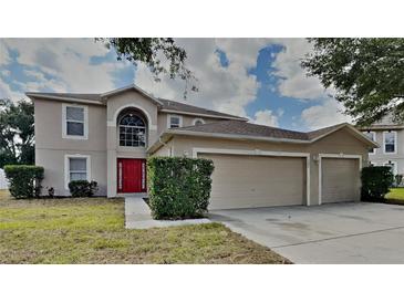 Charming two-story home features a red front door and a spacious three-car garage at 105 Evergreen Dr, Auburndale, FL 33823