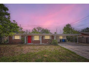 Charming single-story brick home featuring a vibrant red front door and covered carport at 3026 Pinedale Ave, Lakeland, FL 33803