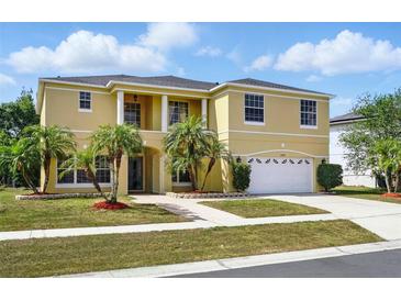Stunning two-story home with manicured lawn, mature palm trees, and a white two car garage at 2523 Jasmine Trace Dr, Kissimmee, FL 34758