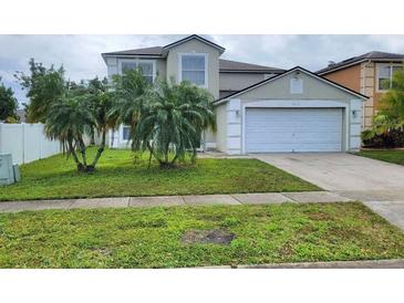 Two-story home featuring a two-car garage, front lawn with palm trees, and neutral-colored exterior at 1416 Aguacate Ct, Orlando, FL 32837