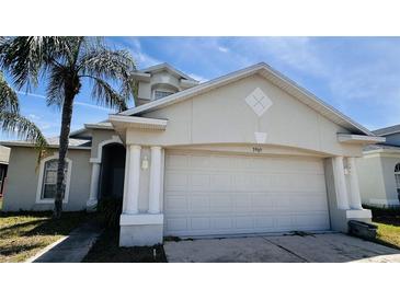 Beige two-story home featuring a two-car garage and a well-maintained lawn at 3965 Hampton Hills Rd, Lakeland, FL 33810