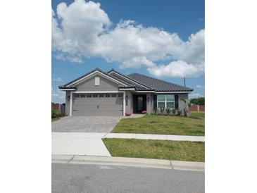 Charming single-story home with manicured lawn, gray siding, and tiled roof under a beautiful sky at 4616 Grandview Glen Dr, Auburndale, FL 33823