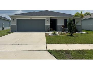 Charming single-story home with a well-manicured lawn, two-car garage, and a welcoming entrance at 1351 Pompay Dr, Davenport, FL 33896