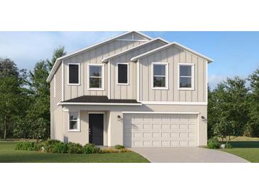 Two-story home features a front-entry two-car garage, landscaped yard, and vertical siding at 1918 Sarah Ln, Winter Haven, FL 33884
