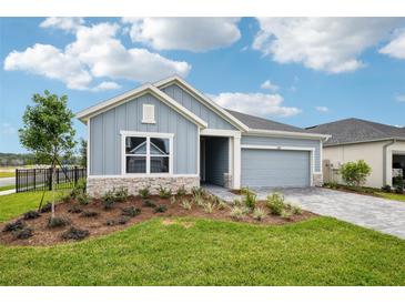 Charming single-Gathering home with light blue siding, stone accents, and a well-manicured lawn on a sunny day at 6087 Sacred Oak Ave, Mount Dora, FL 32757