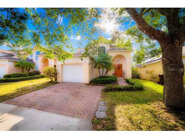 Charming two-story home with a brick paved driveway, well-manicured lawn, and mature landscaping at 1142 Mariner Cay Dr, Haines City, FL 33844