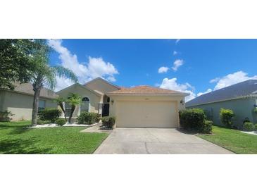 Charming single-story home featuring a manicured lawn and a two-car garage at 14845 Huntley Dr, Orlando, FL 32828