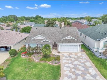 Well-maintained home with lush landscaping, charming flowerbeds, and a unique patterned driveway at 1709 Latta Ct, The Villages, FL 32162