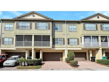 Townhouse with a one-car garage, brown shutters, a screened balcony, and neat landscaping at 2352 Grand Central Pkwy # 18, Orlando, FL 32839