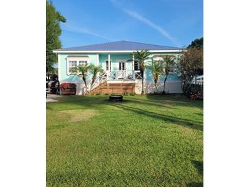 Charming beach house with a blue exterior, inviting porch, and lush green lawn at 166 Catfish St, Haines City, FL 33844