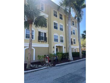 Inviting three-story condo building surrounded by lush palm trees and vibrant landscaping at 10091 Lake Cove Dr # 301, Fort Myers, FL 33908
